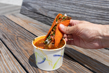Handheld Birria Taco Dipped into a Side of Consomme