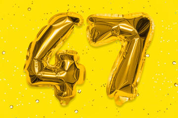 The number of the balloon made of golden foil, the number forty-seven on a yellow background with sequins. Birthday greeting card with inscription 47. Numerical digit, Celebration event, template.