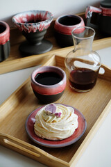 Pavlova dessert and coffee served in a purple-red designer ceramic pottery dishes