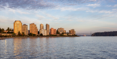 Fototapeta premium Walking Trail in a modern city on the West Coast of Pacific Ocean. West Vancouver Centennial Seawalk, British Columbia, Canada. Sunny Summer Sunset.