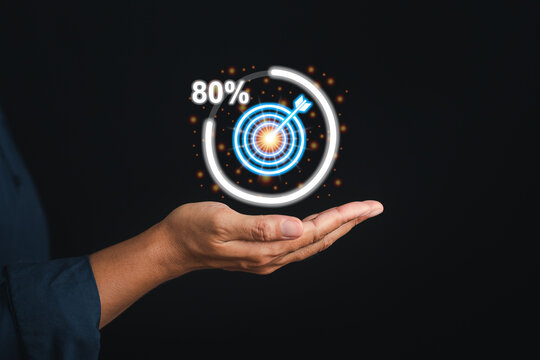 Targeting and achieving a goal in business concept. Digital image of target icon progress for business achievement on the palm of a businessman while standing with black background in the studio