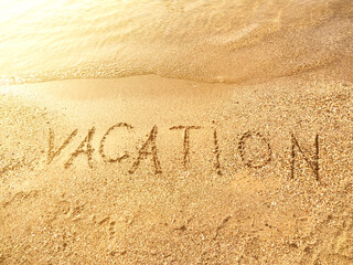 The word Vacation is written on the beach
