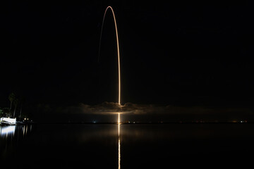 Rocket launch long exposure streak shot with reflection on the water