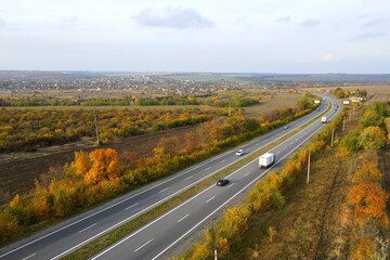 White trailer car driving on asphalt road. Road seen from air. Aerial view landscape, dron...