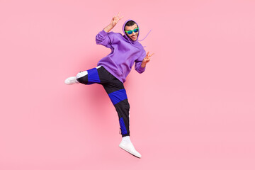 Fototapeta na wymiar Full body photo of funny young brunet guy jump wear eyewear hoodie pants shoes isolated on pink background