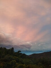 Sunset -  between small mountains - with different shades of pink and blue.
