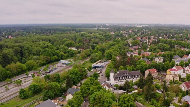 Aerial photos in a scenic flight of Neuenhagen, a small town in Germany in the federal state of Brandenburg. You can see many green trees, small houses and a railway line.