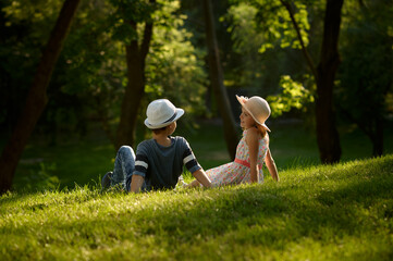 Boy and girl with air balloons sitting on a grass