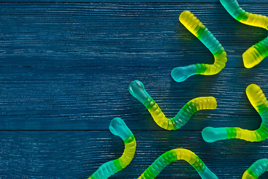 Blue and Yellow Gummy Worms on Blue Wood Background