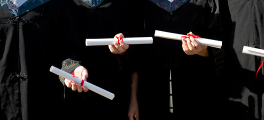 people in a gown holding a diploma.
