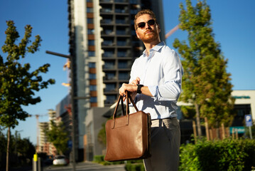 Young businessman with briefcase. Handsome man in suit watching at wristwatch.