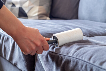 Sticky lint roller on fabric furniture removing cat hairs.  hair remover.