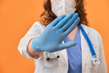 Hand of a medic in a sign of prohibition. Close-up of a doctor in protective gloves and a medical...