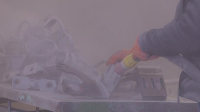Sandblast metal parts. The man is sandblasting the detail. Sandblasting gun