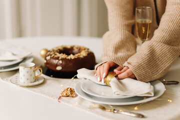 A woman hostess in a knitted cardigan sets plates on the table food and drinks decorates the dining...