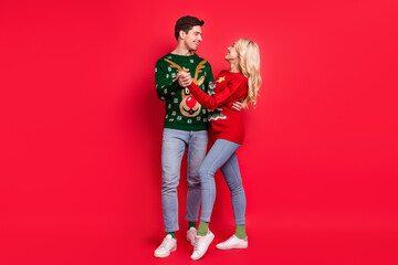 Photo of carefree couple in love dance wear ugly pullover jeans footwear isolated red color background