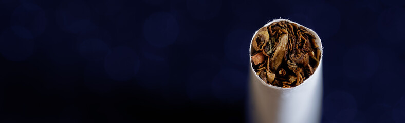 The tip of a cigarette on a dark background. View from above. Free space for an inscription. Bokeh. Web banner.