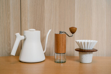 Coffee brewing equipment, Dripper set on a wooden table, Making home coffee concept. White kettle, Wooden manual hand grinder and Ceramic dripper