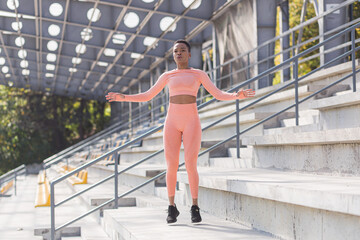 Woman doing burpee exercise, young African American woman doing fitness and active lifestyle in the morning, outdoors near the stadium
