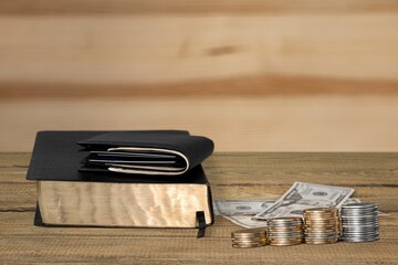 The biblical concept. Golden money on a wooden table with Holy Bible.