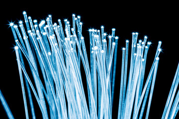 Bundle of optical fibers with blue light. Black background.