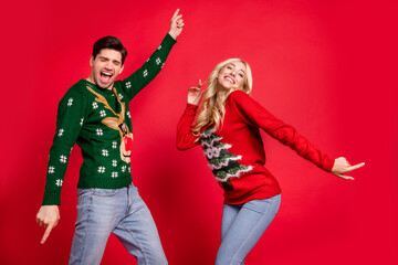 Photo portrait laughing couple wearing sweaters dancing at xmas party celebrating holidays isolated vivid red color background