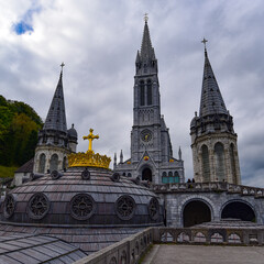 Obraz premium Lourdes, France - 9 Oct 2021: Gold gilded cross atop the dome of the Basilica of Our Lady of the Rosary in Lourdes