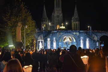 Fototapeta na wymiar Lourdes, France - 9 Oct 2021: Pilgrims attend the Marian Torchlight Procession service at the Rosary Basilica in Lourdes