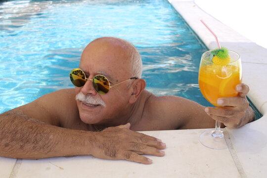 Bald senior man with mustache and sunglasses in hotel swimming pool