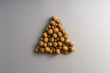 Fototapeta na wymiar Brazilian nuts, walnuts, almonds shaped as Christmas tree on Winter and Christmas grey background
