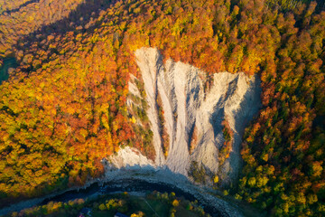 Aerial view of the huge elephant  rock in carpathian mountains at sunset. Colorful autumn aerial view. Aerial photo of mountains and trees colored into fall colors in small town Yaremche, Ukraine