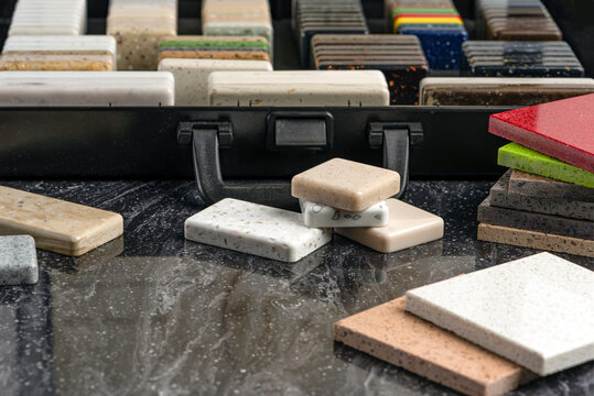 Large selection of stone samples for countertops and floors. Pieces of artificial acrylic stone in a sample box. A set of shades of countertops of different textures