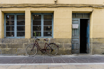 Fototapeta na wymiar Bicycle resting on the facade of an old house with a door and two windows
