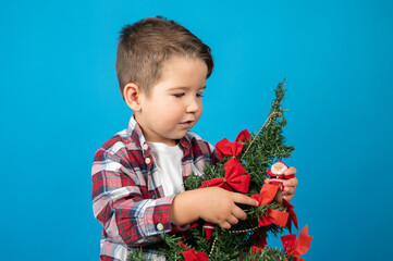 Waiting for christmas. Cute little boy examines a Christmas tree decorated with red bows
