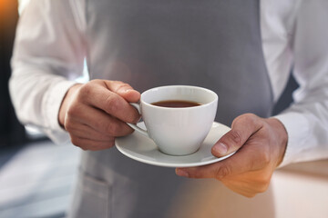 A man holds a white cup with a hot drink outdoors. A man's hand holding a mug of coffee. Close-up, image layout, place to copy text. High quality photo