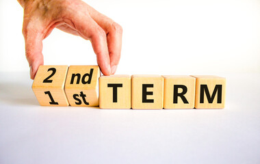 First or second term symbol. Businessman turns wooden cubes and changes words '1st term' to '2nd term'. Beautiful white table, white background. Business and first or second term concept, copy space.