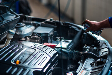 a Technician is spraying the maintenance oil to car engine - obrazy, fototapety, plakaty