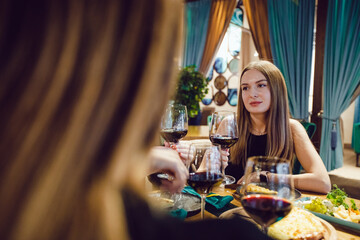 Young woman drinking wine with girlfriends in a restaurant.