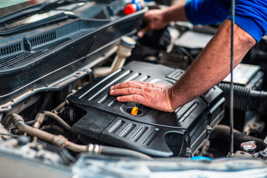 Laborer concept, a very experienced car technician is inspecting the car engine.