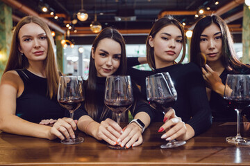 Four beautiful women are drinking wine in a restaurant.