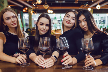 Four beautiful women are drinking wine in a restaurant.