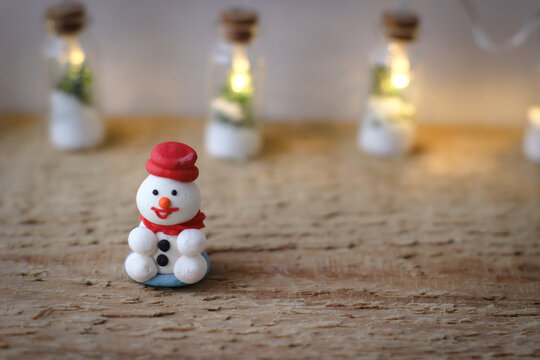 Christmas decor. A miniature figure of powdered sugar snowman with a red hat on a wooden board.