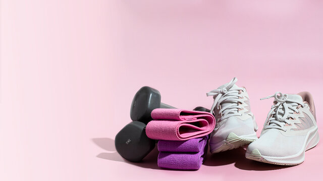 Different resistance booty bands,  anddumbbells, and  femaly sneakers on large background for banner.Sport at home concept