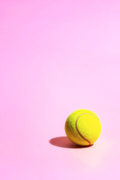 Bright yellow tennis ball on the pink background.Copy space