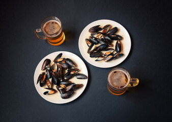 Plates with mussels and mugs of beer. Top view.