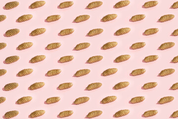 Gold color pine cones pattern on pale pink background. Creative concept. Autumn and festive minimal design.