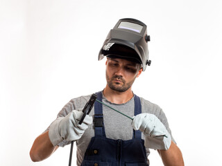 A man with a welding mask on his head, raised up, open face, holding welding wires and an electrode...
