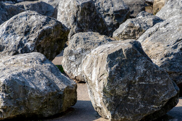 Selective focus of black grey stone on the ground, Big rocks in the park with sunlight, Abstract pebble stones background.