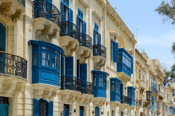 Residential house facade with traditional Maltese navy blue enclosed wooden balconies in Valletta,...