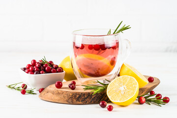 Cranberry tea with lemon and rosemary in glass mug. Healthy hot vitamin drink.
